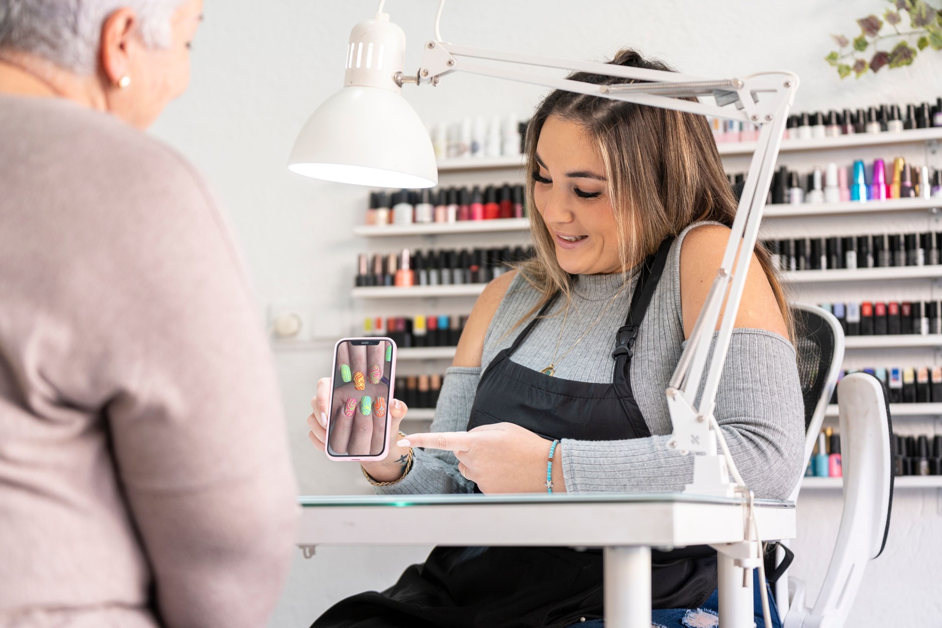 Real female manicurist showing a nail painting design with a smartphone
